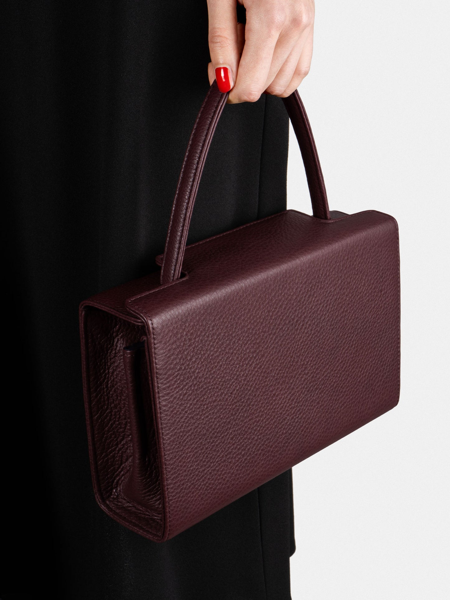 Woman holding a burgundy TSATSAS 931 crossbody handbag with top handle