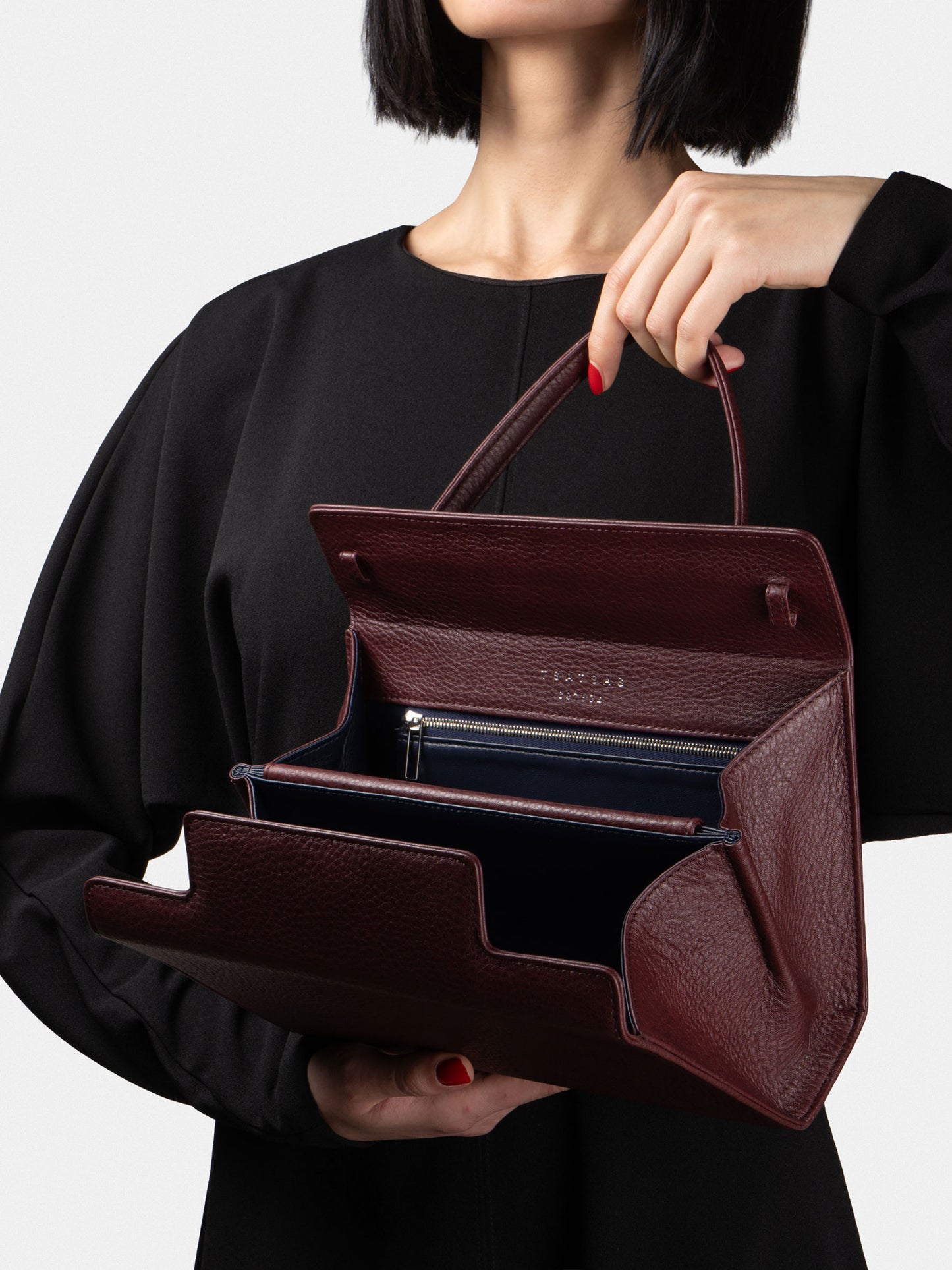 Woman holding an open burgundy TSATSAS 931 crossbody handbag with top handle
