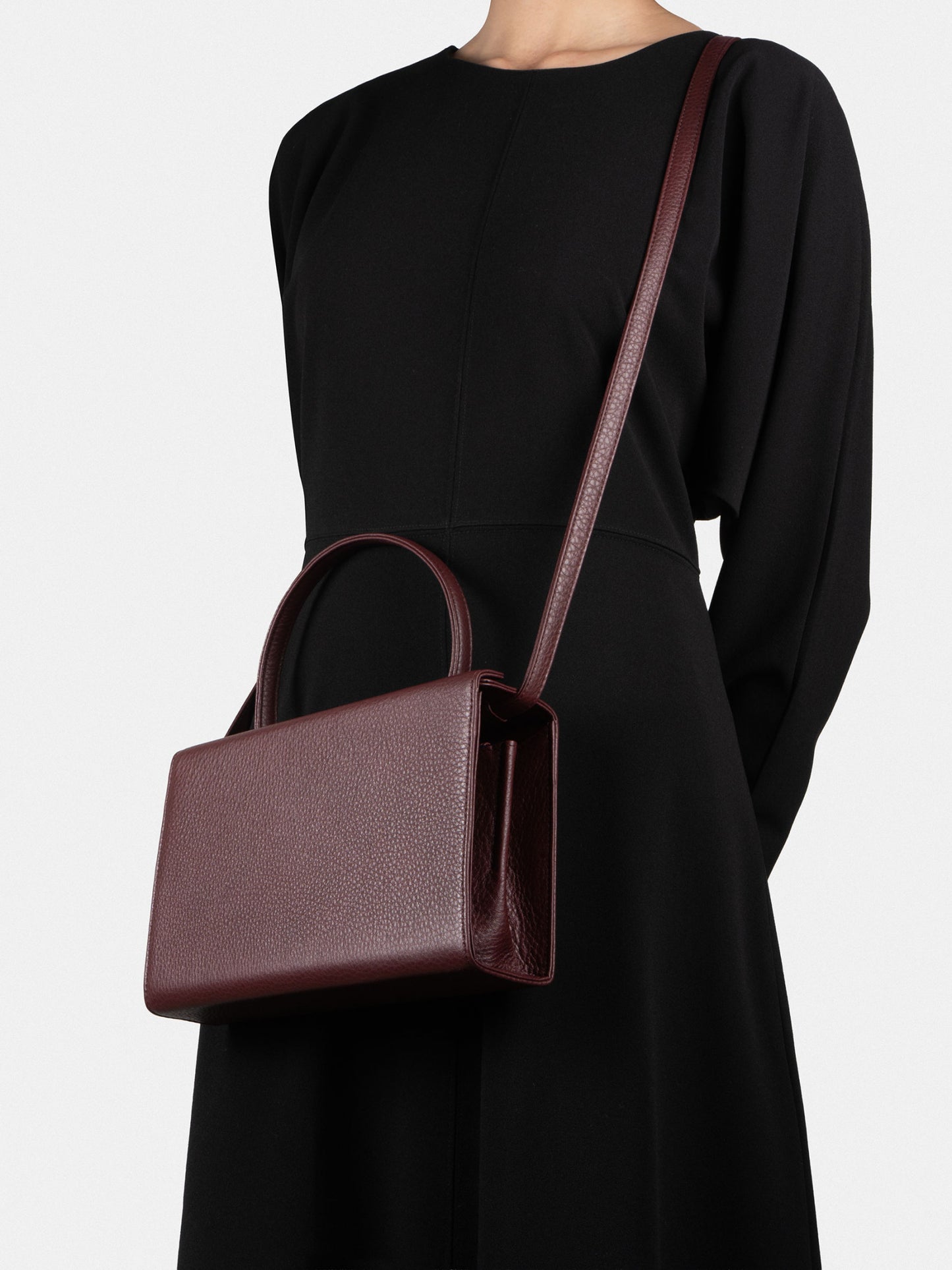 Person wearing a black dress with a burgundy TSATSAS 931 crossbody handbag 